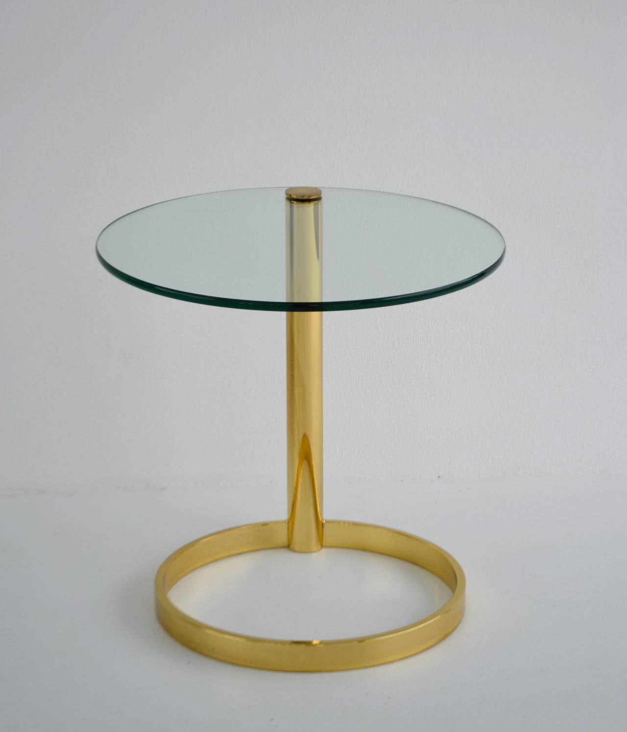 Stunning Post-Modern polished brass round side table with glass top, circa 1970s-1980s by Pace. This sculptural architectural occasional table is designed with a brass column support and cantilevered swivel glass top.
