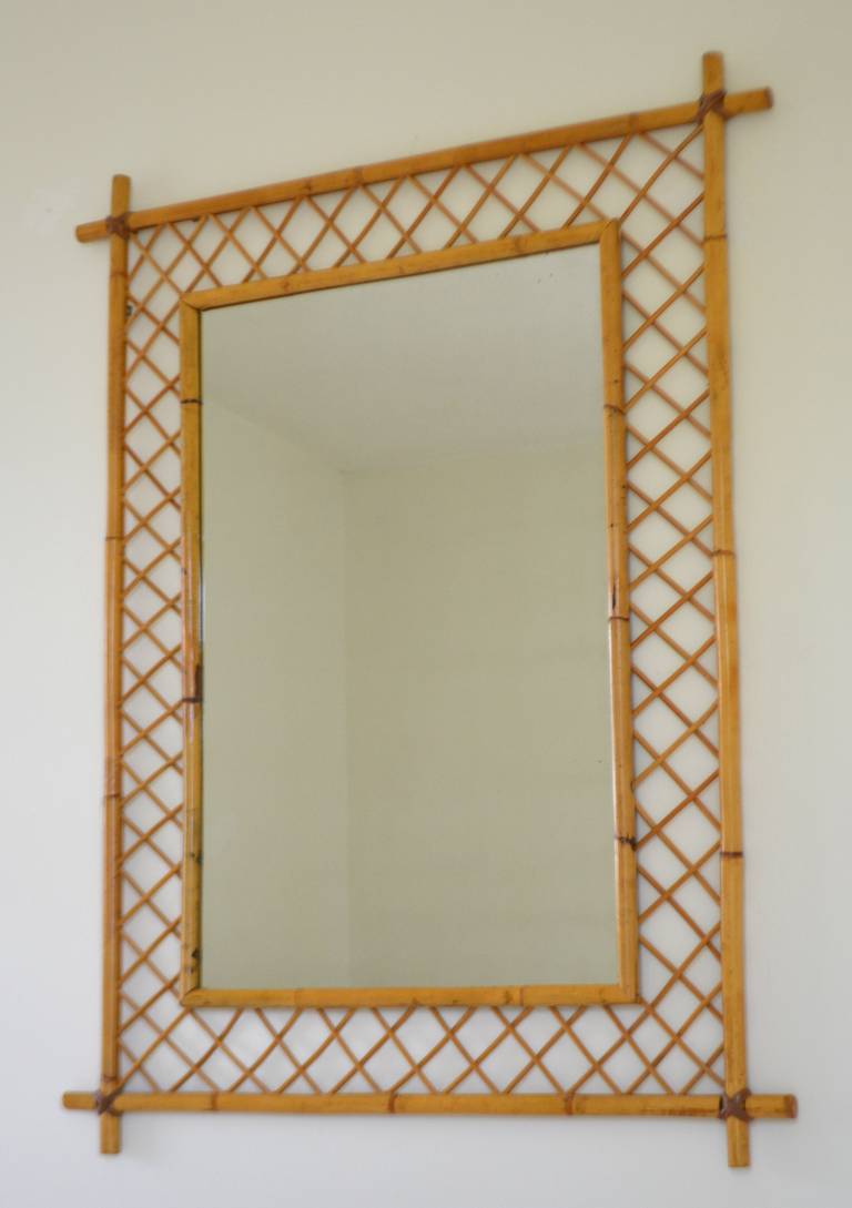 Striking Mid-Century bamboo and reed wall mirror, circa 1960s-1970s. This highly decorative rectangular form mantel mirror is designed with open fretwork and rawhide strap details. Dimensions are 37