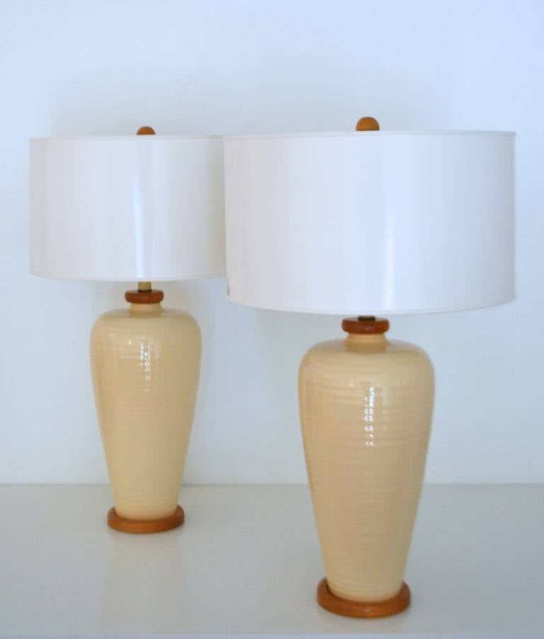 Pair of Mid Century Modern hand thrown butter glazed ceramic jar form table lamps, c. 1950s -1960s. These handsome ridged lamps are mounted on custom oak bases and matching capitals. Sold without shades.
Measurements: 
Overall: 9