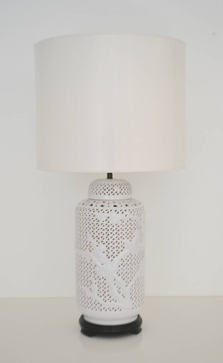 Stunning Hollywood Regency Asian inspired reticulated Blanc de Chine Table lamp, c. 1940s -1950s. This incredible pierced porcelain table lamp accented with foliate decoration is mounted on an ebonzied base and wired with brass adjustable fittings.