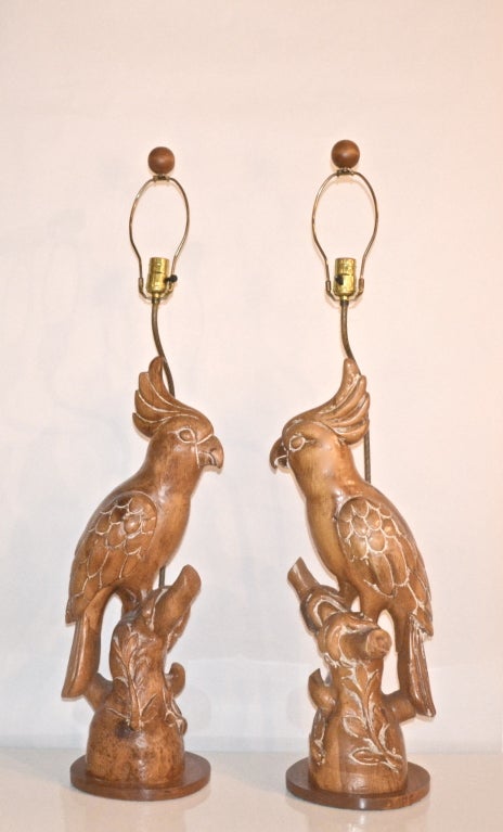 Rare and unusual hand carved sculptural wooden parrots mounted as table lamps. These one of kind artisan crafted figural cockatoo lamps are wired with brass hardware. c.1950s. Shades not included.