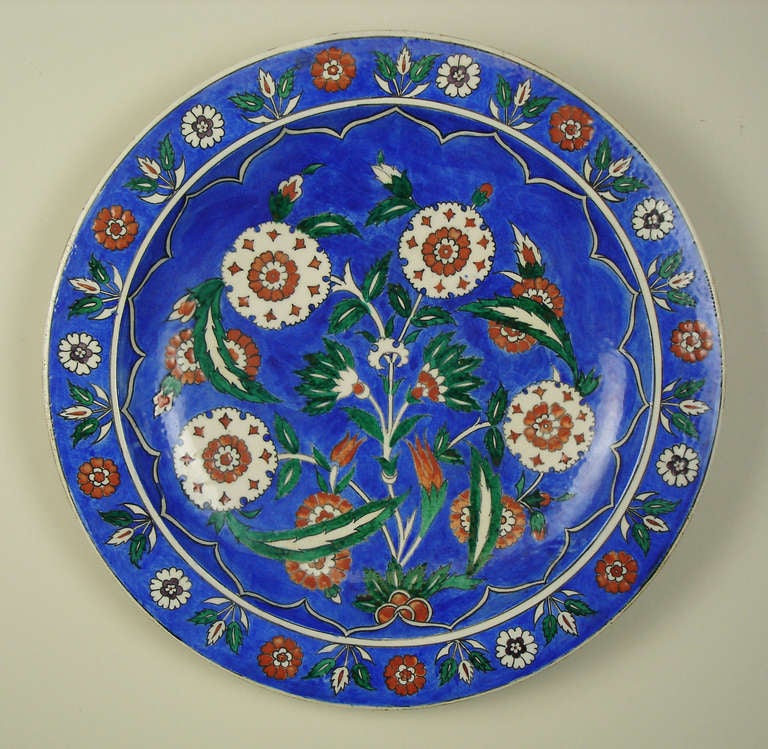 an iznik style faience charger with floral designs on a blue ground .