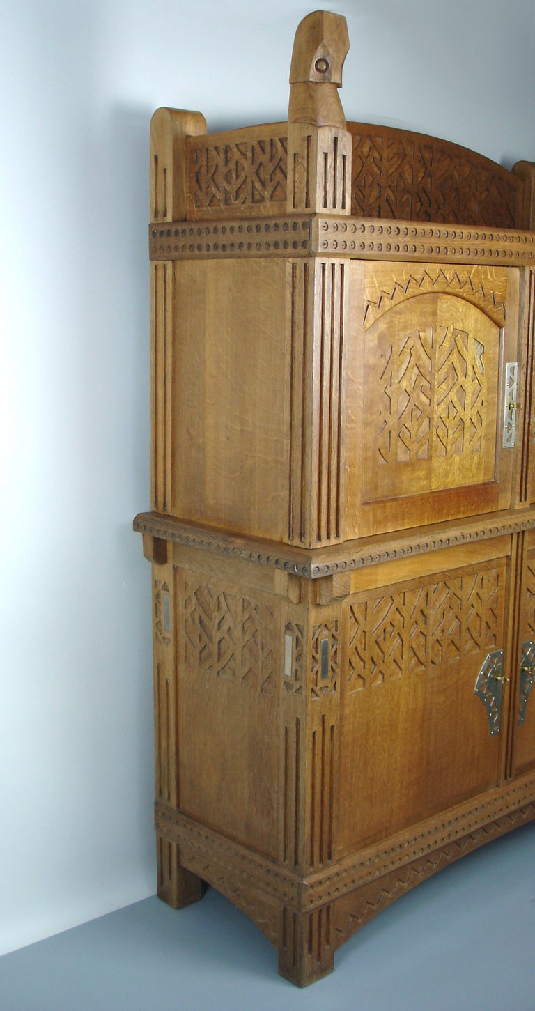 an oak cabinet with carved ornamentations representing 2 stylized owls on the top,branches,  winding, stripes &circles motives.
4 fir shelves inside