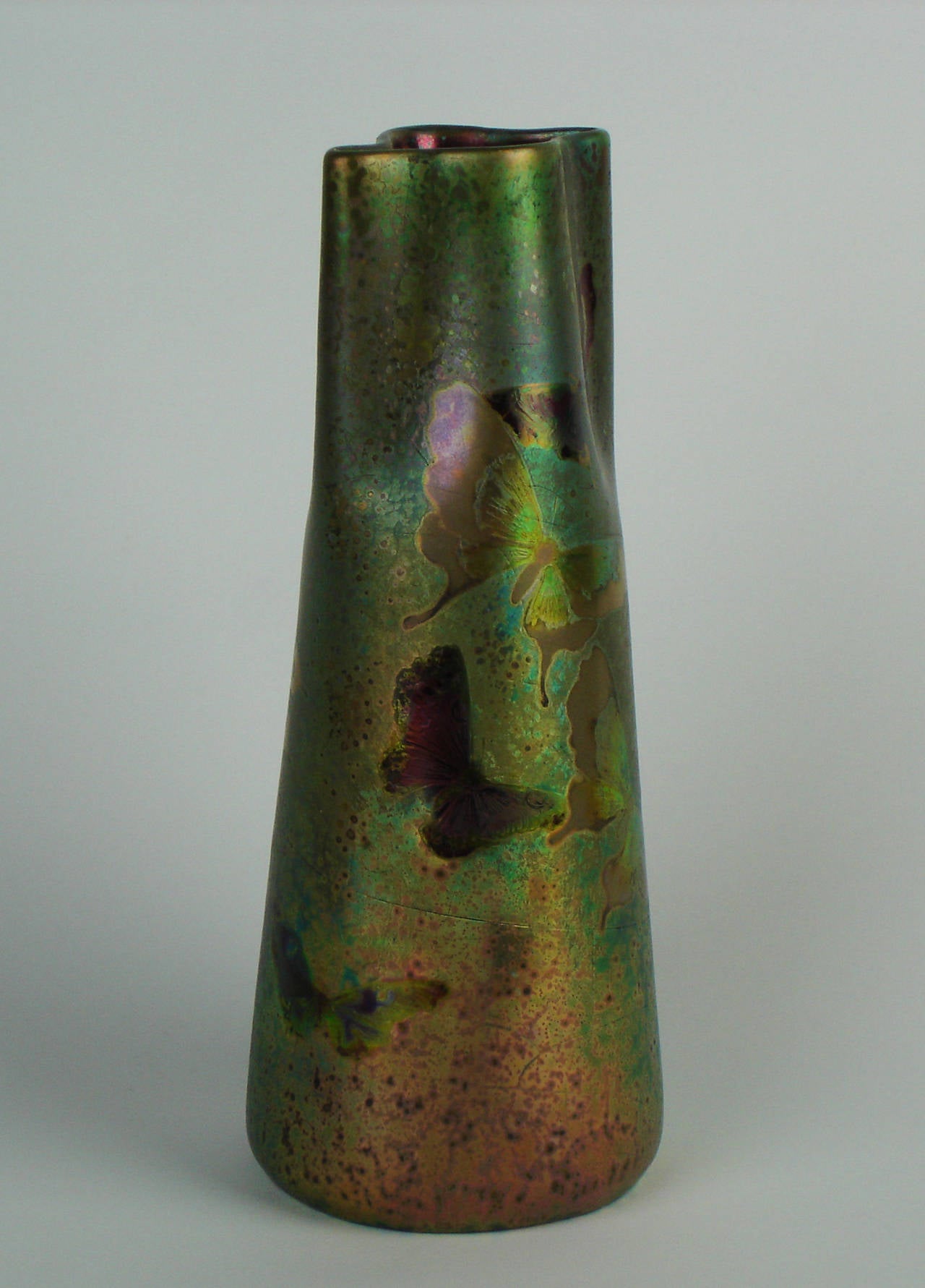 An Art Nouveau ceramic vase by Clement Massier with a luster varying from purple yellow and different shades of green presenting a festive decoration of multicolored twirling butterflies on a greenery background. Signed Clement Massier, Golfe Juan.