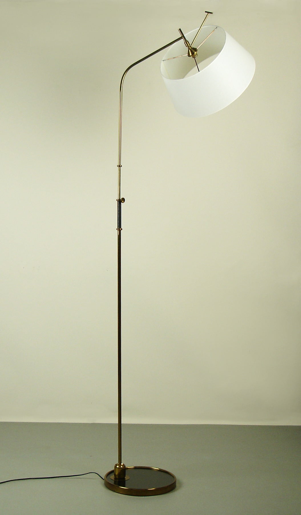 Floor lamp by Lunel with swivelling shade & rod,an adjustable height.The base is in  black laminate circled with brass,a black leather handle is on the brass rod.The lamp shade is new ,similar to the original.