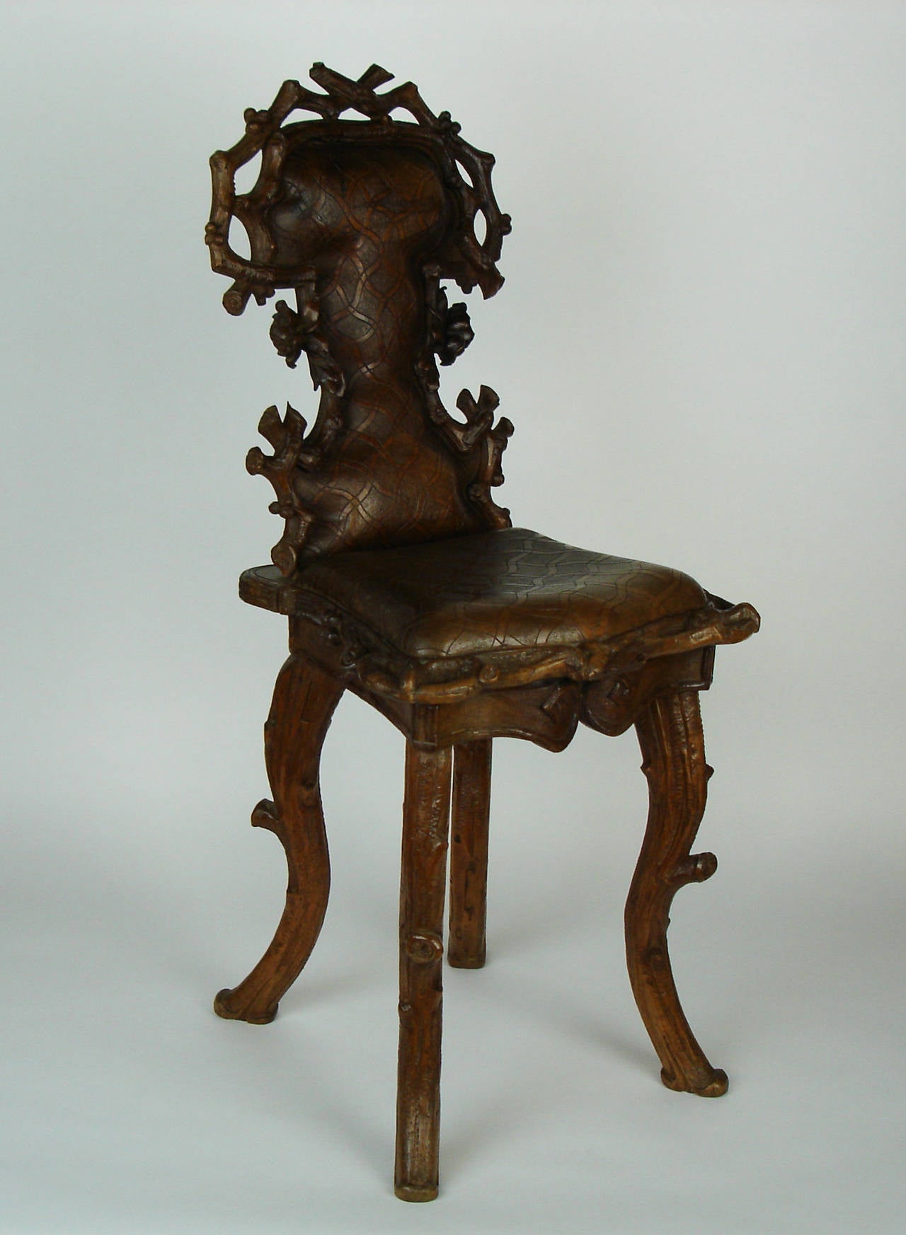 A Black Forest chair in carved lime; branches and roses sculpted on the back, a trompe l'oeil checked cloth on the seat and the back. The seat open on a box (formerly, a musical box).Produced in Brienz (Switzerland).