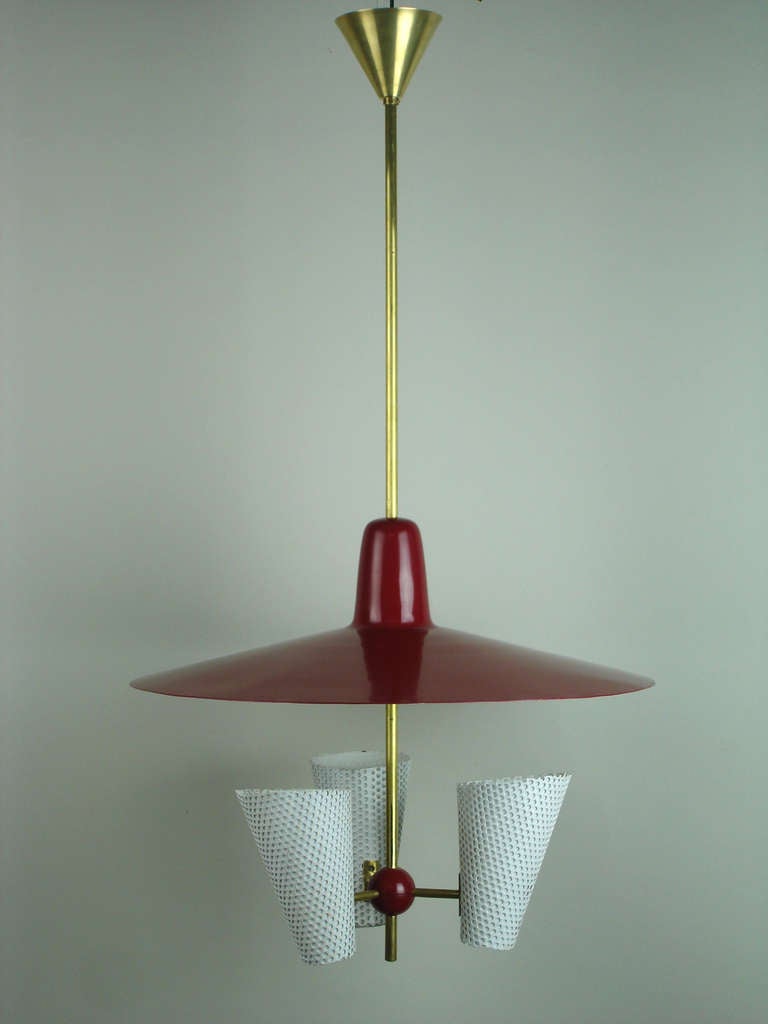 3 painted white perforated metal shades under a red & white painted reflector hold with  brass rods converging on a red plastic ball.The reflector is adjustable on the central rod.