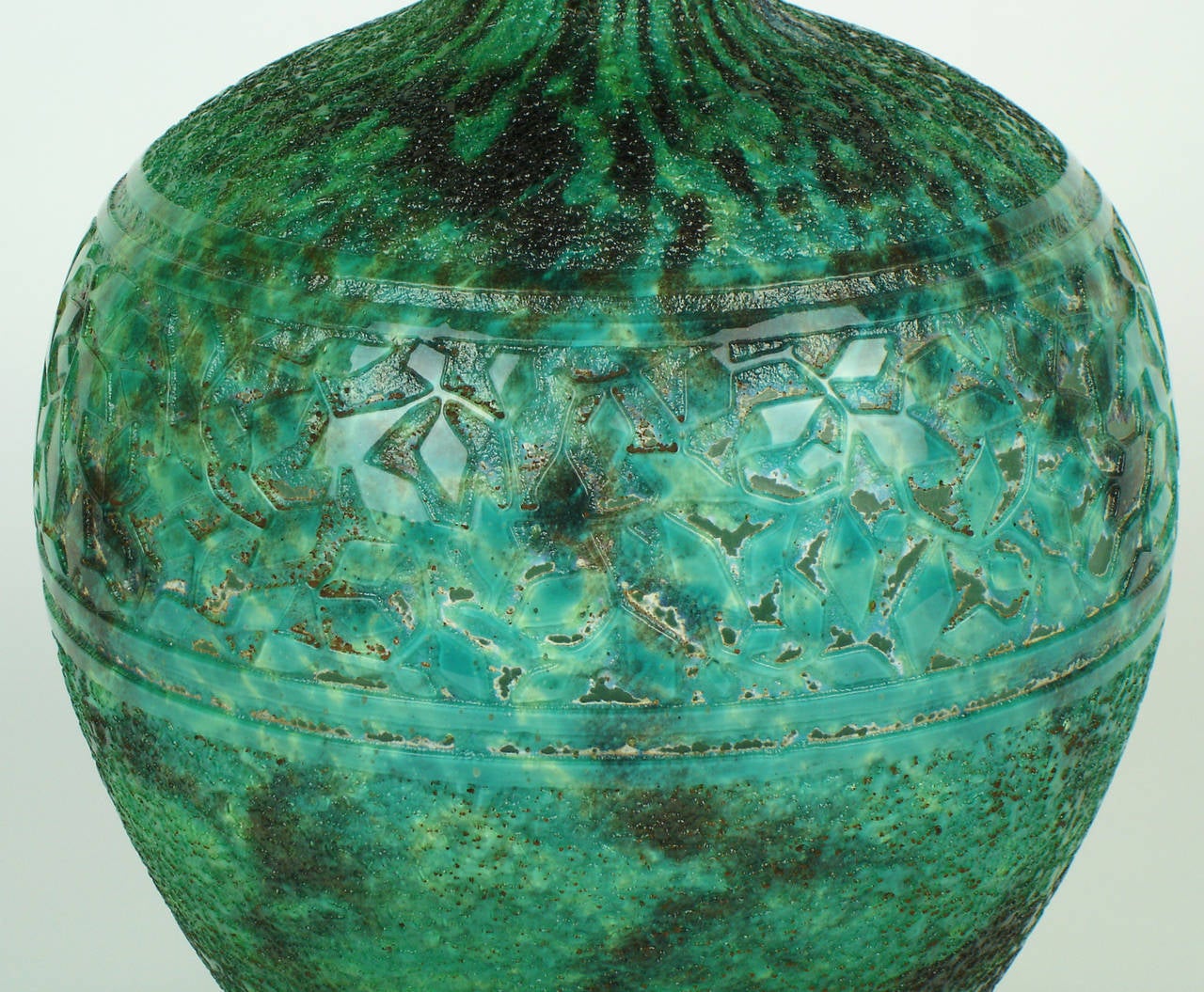 A flattened circular form,acid etched vase in green glass internally decorated with white & different kinds of green,the middle part decorated with geometric leaves and textured surface on the upper and lower part.Mark Daum,croix de
