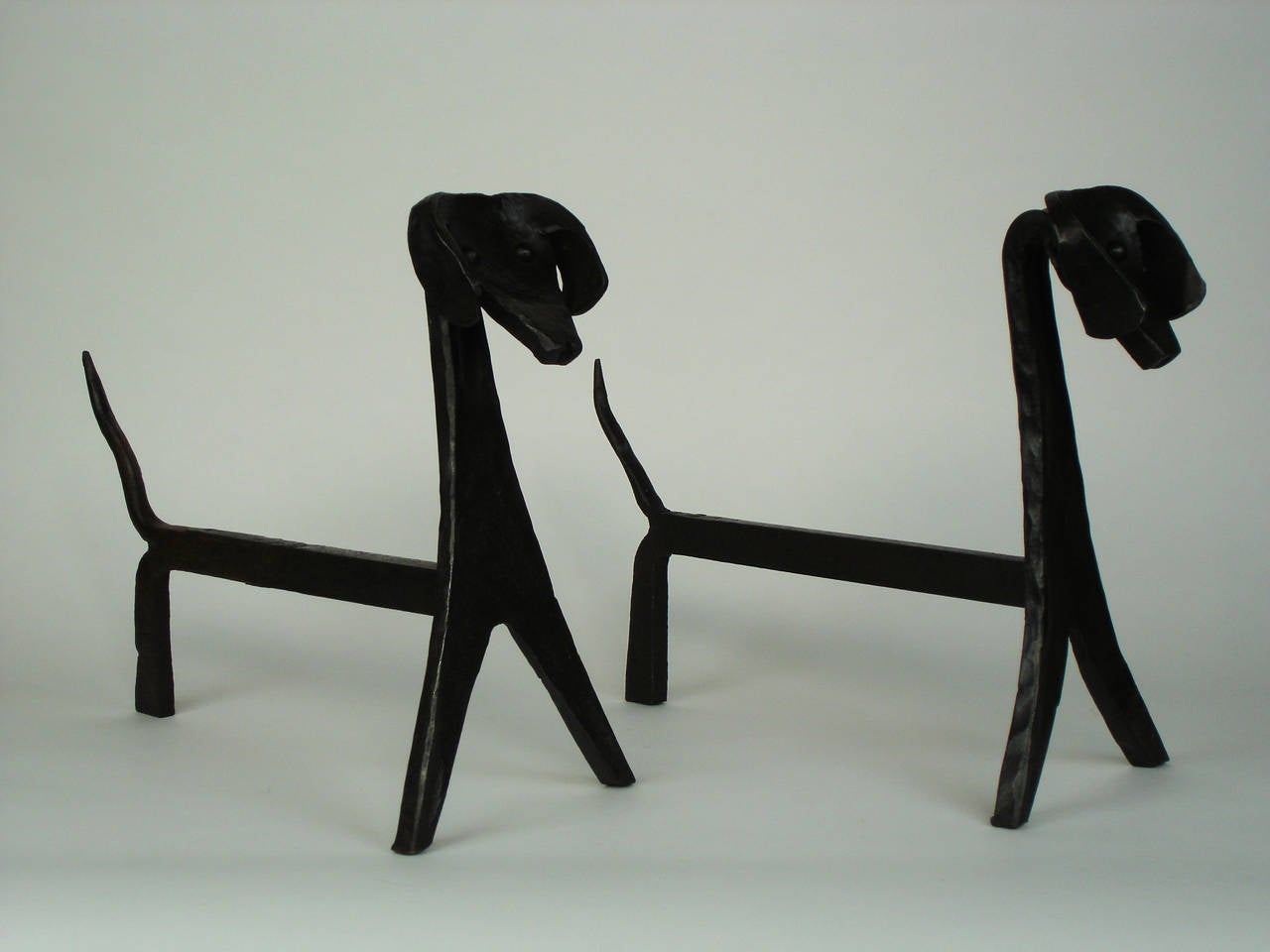 Two wrought iron andirons in shape of stylized dog.