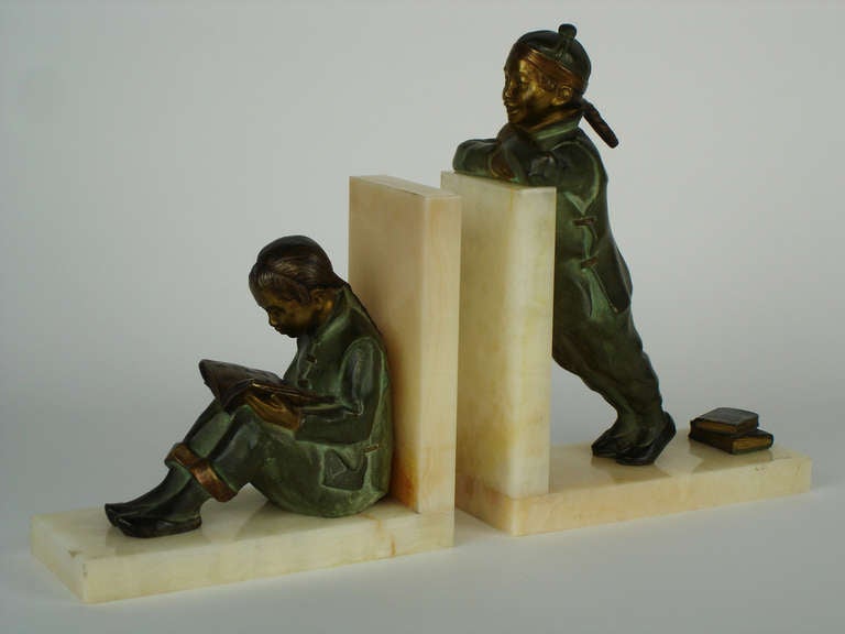 Green & gold patinated bronze bookends representing two chinese children on albaster bases.