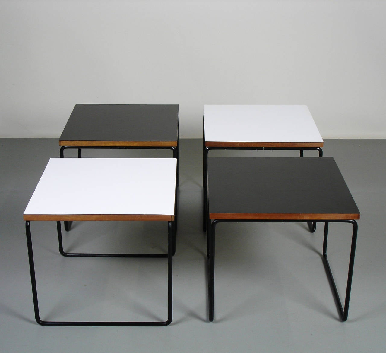 4 side tables or coffee tables  by Pierre Guariche with a base forming structure in black enamelled steel wire,tops in wood plated black or white formica.Marked Steiner