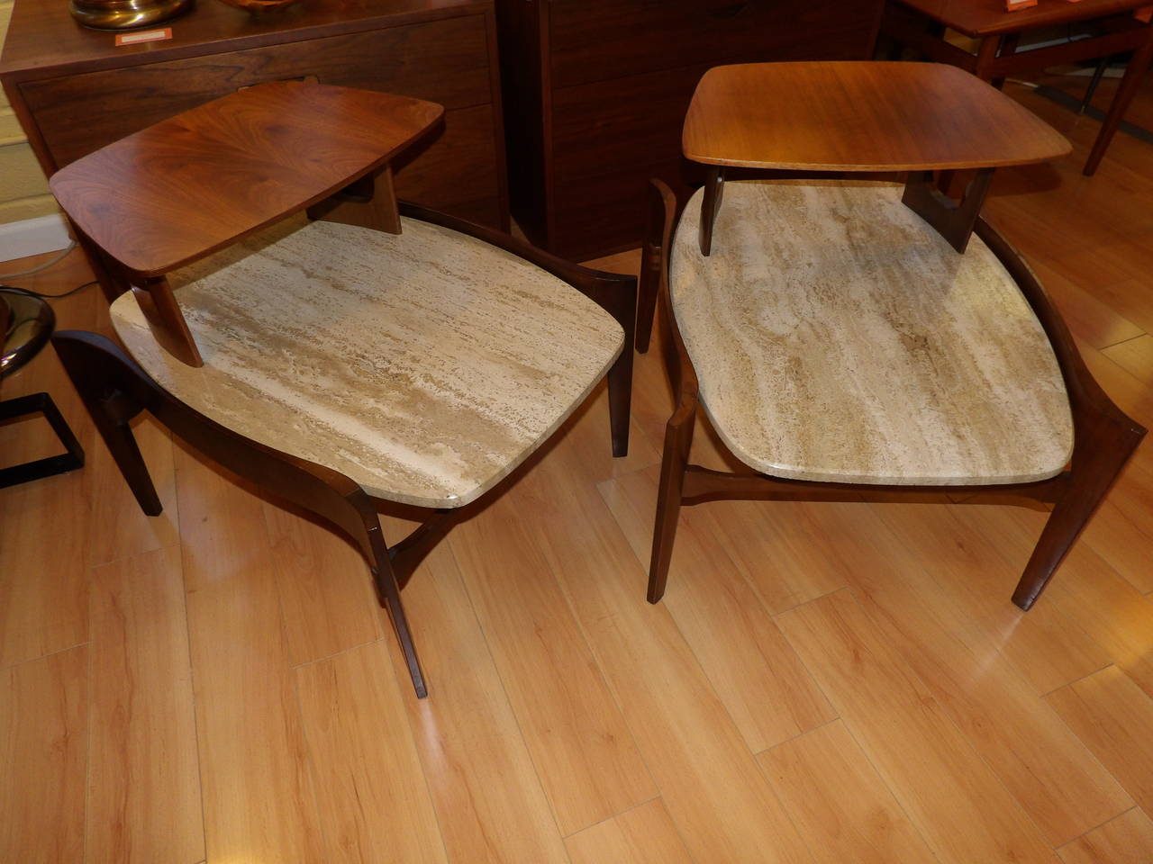 A striking pair of step-end tables designed by Bertha Schaefer for Singer & Sons. Beautiful sculptural walnut frames with oblong oval shaped travertine tops. Measurement to travertine top 14
