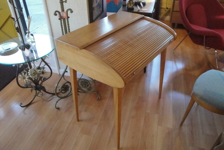 1960's Heywood Wakefield tambour desk. Rolltop opens to access writing surface with pigeon hole fitted interior. Streamline design with asymmetrical profile. Matching desk chair included with purchase.  