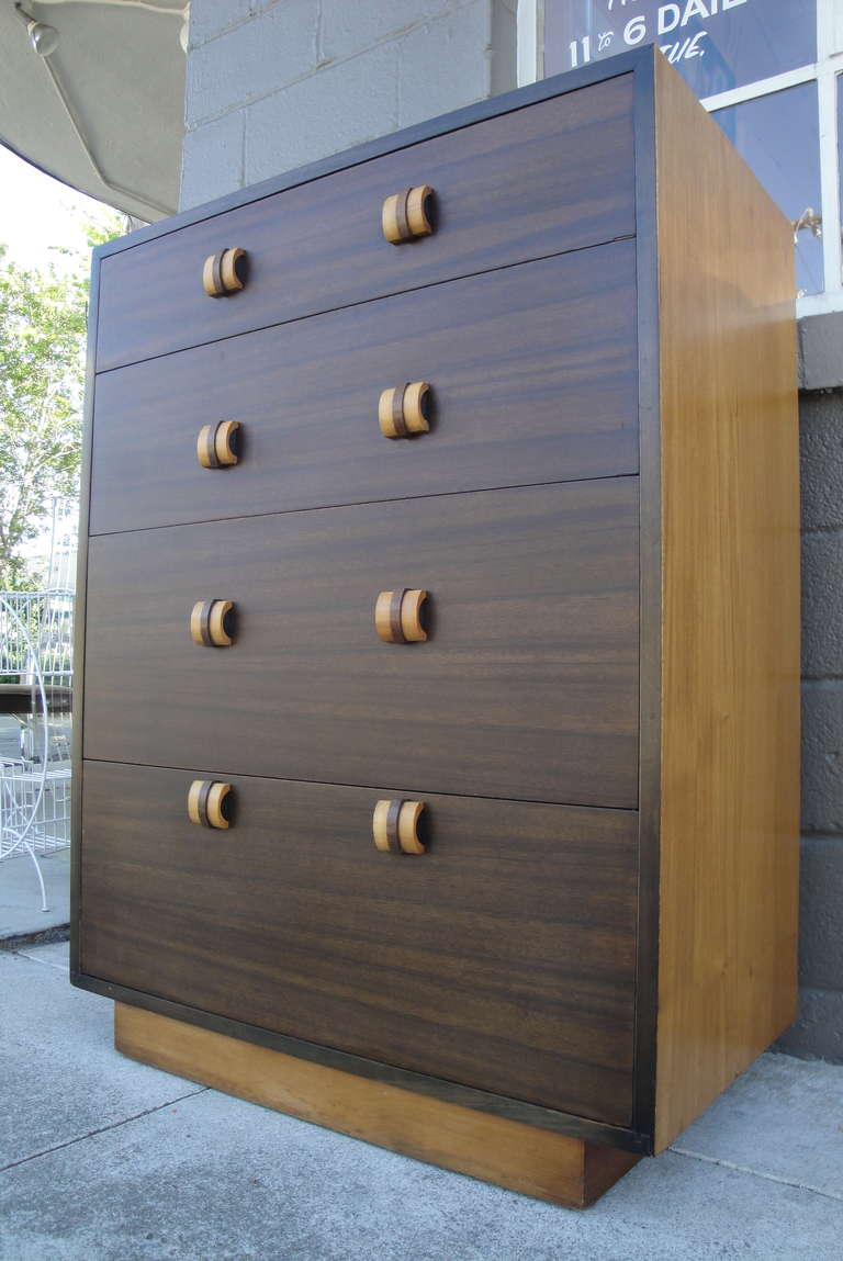 A limited edition highboy dresser designed by Gilbert Rohde for Cavalier Furniture. Retaining its original finish with a unique two-tone walnut veneer. Bamboo like banded pulls, ribbon cut mahogany interior and dovetail construction. A fine and
