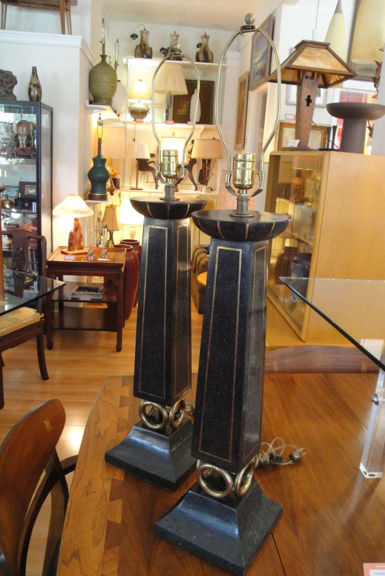 A monumental pair of faux stone column table lamps with brass ring and inlaid brass detail.