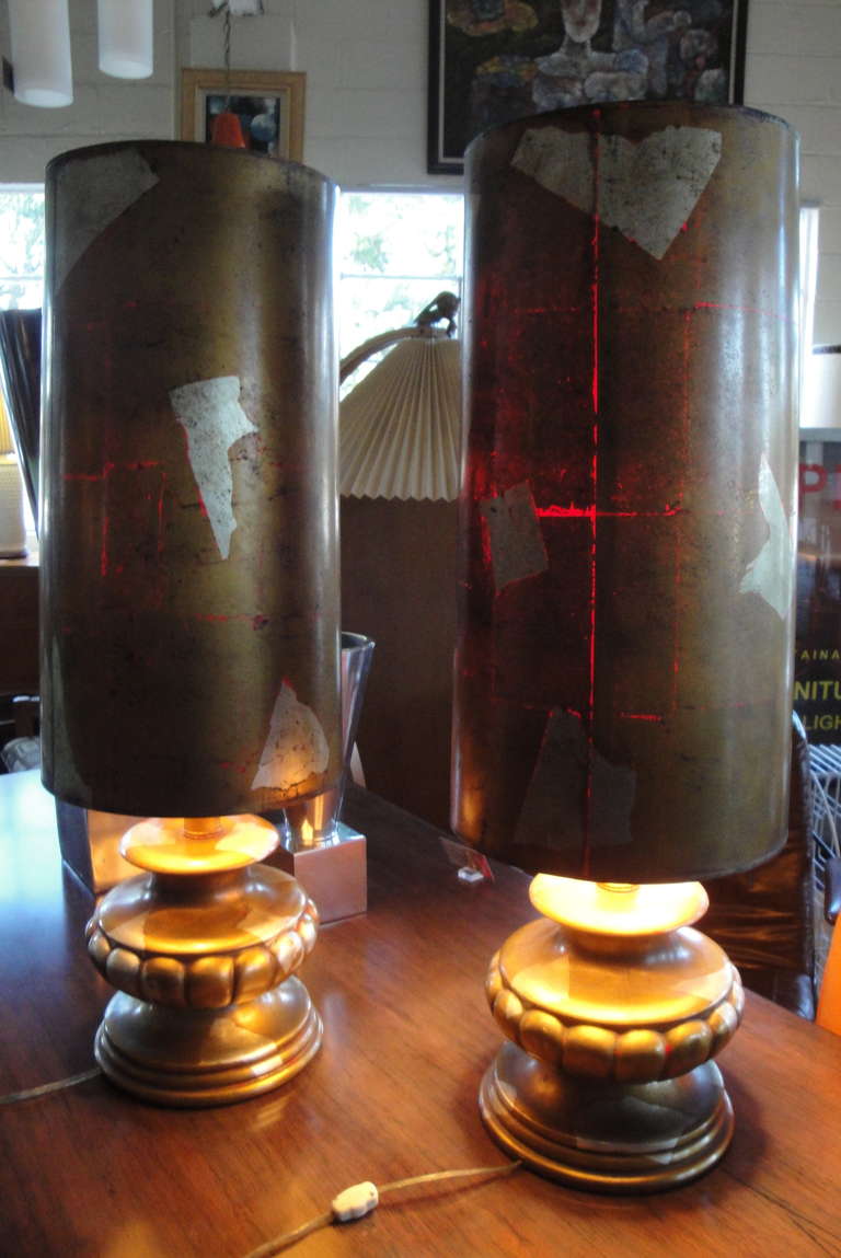 A pair of gold and silver leaf lamp shades and bases. When illuminated notice red detail that shines through leafing pattern. An almost captivating transformation and effect from off to on position.