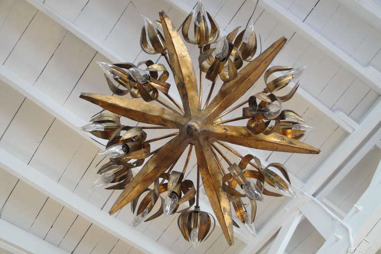 Unusual floral motif eighteen-light Brutalist chandelier. Retaining original finish with a gold leaf organic and textural patina. Original escutcheon plate and chain. Original wiring needs replacement.
