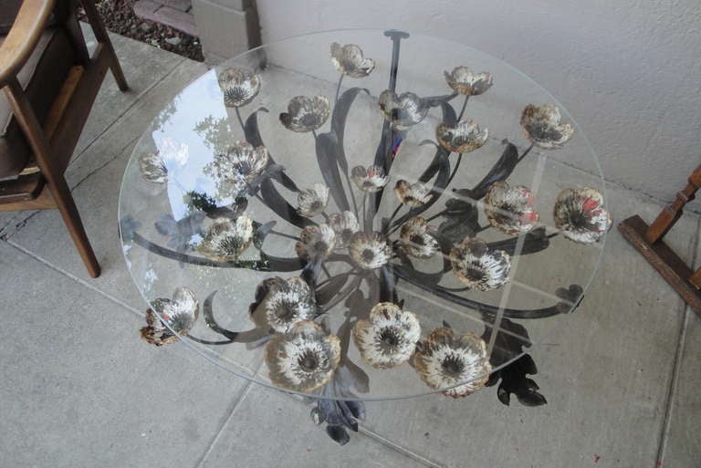 Italian floral coffee or end table made of painted iron with a glass top. Dramatic design with a boquet of over-sized flowers reaching toward the top surface.