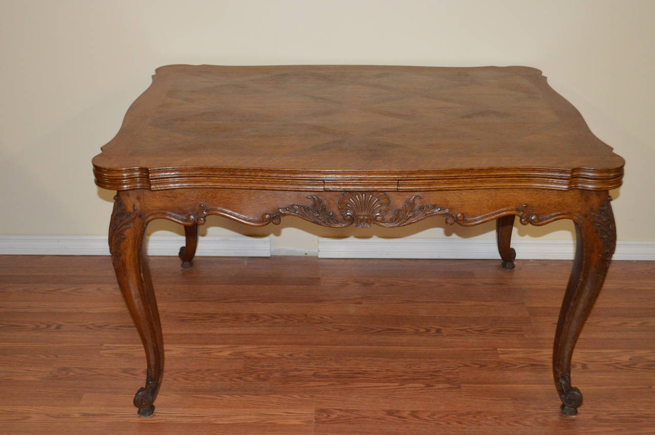 Louis XV style Provençal dining table made of solid oak base with a inlay oak parquetry top. There are two leaves that are tucked under the table plateau and slide in and out. When the two leaves are pulled out you can sit eight to ten depending on