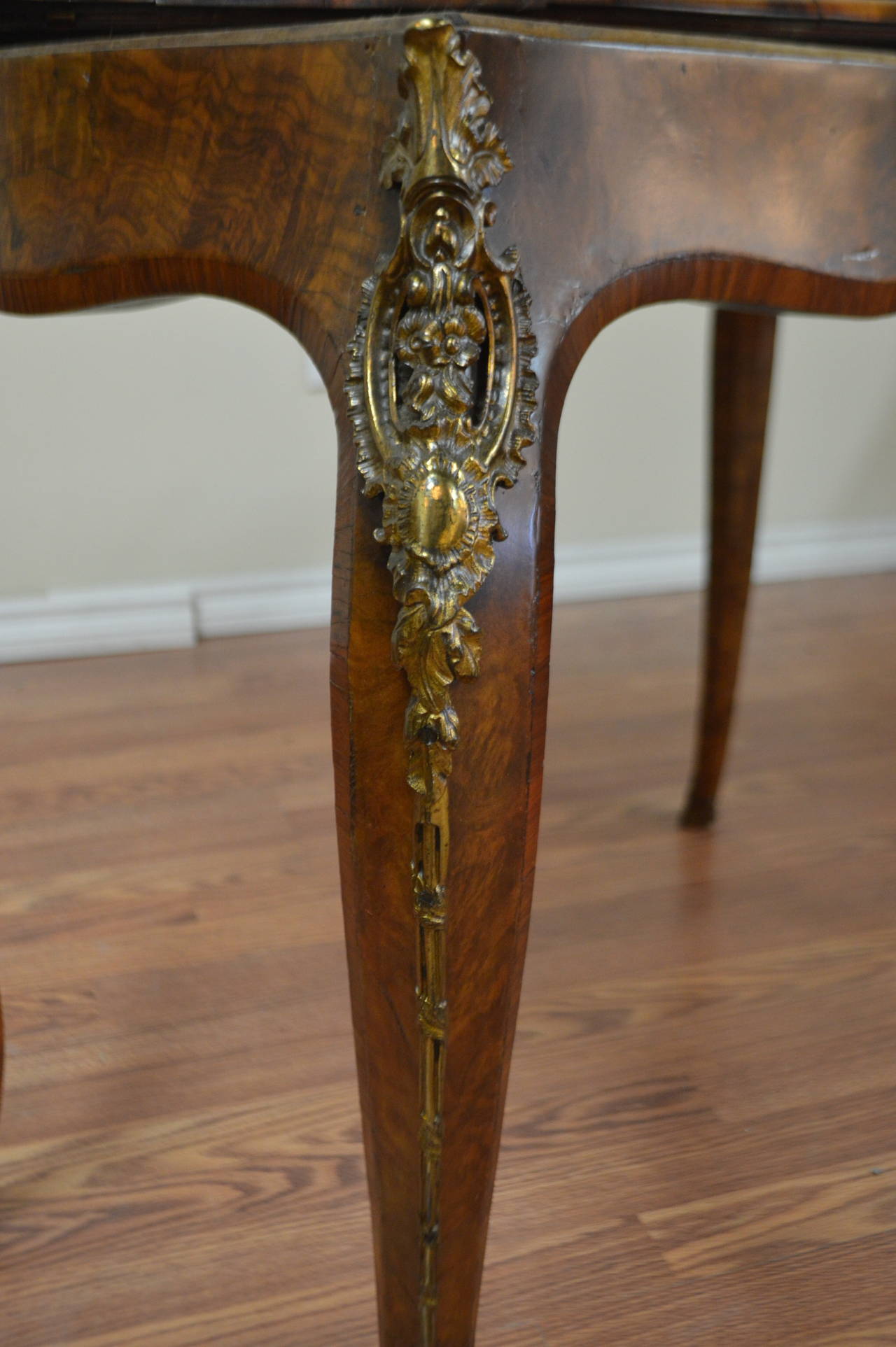 A fine quality burled mahogany games table with bronze details on all legs. The table makes a fine console while not being used as a games table.
The table top pivots to one side and opens to a good size table. The felt is in good condition and has