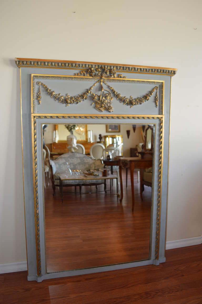 A beautiful French blue painted Louis XVI style trumeau with fine hand carved gilded details typical of the Louis XVI style. The mirror is not original.