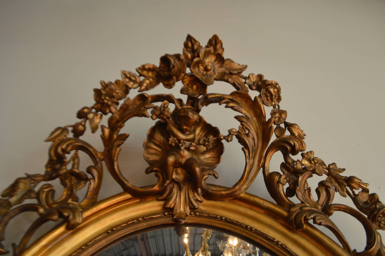 Amazing 19th century ornate gilded oval mirror. The oval frame is gilded over wood and all the hand-carved elements are in wood and plaster.
The beveled mirror shows some age but might not be original.