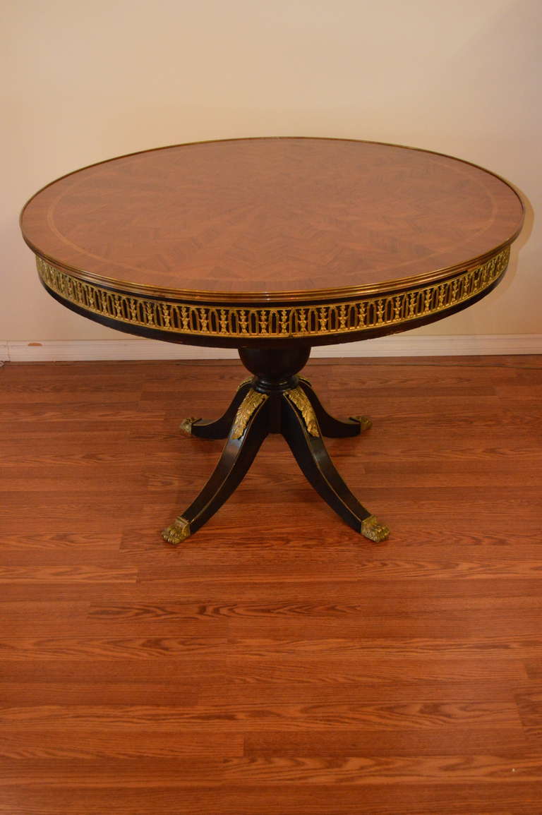 This round pedestal hall table has a beautiful patterned inlay wood top.
The base is of mahogany and there are extensive gilded metal decorative elements on the apron and on the pedestal.