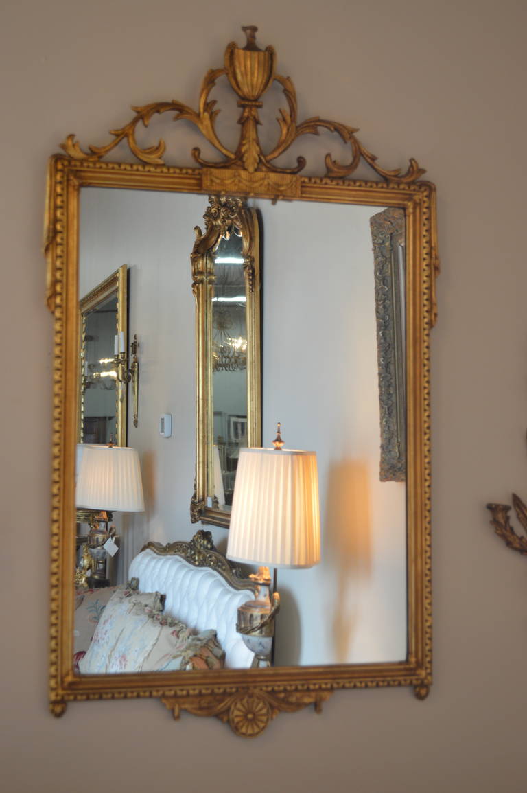 Neoclassic style gilded mirror, having simple and elegant hand-carved details. The mirror is not antique.