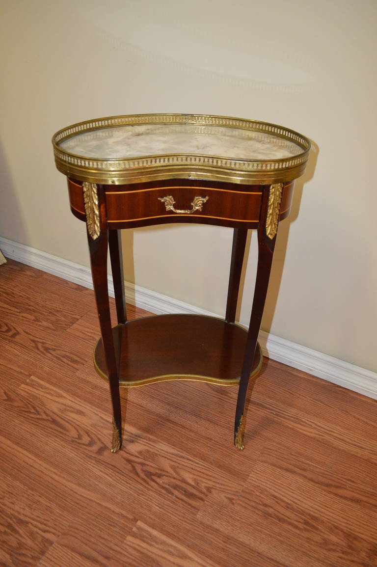 Lovely small  and easy to place kidney shape side table made of inlay wood.
Adorned with bronze gallery and details with a marble top.