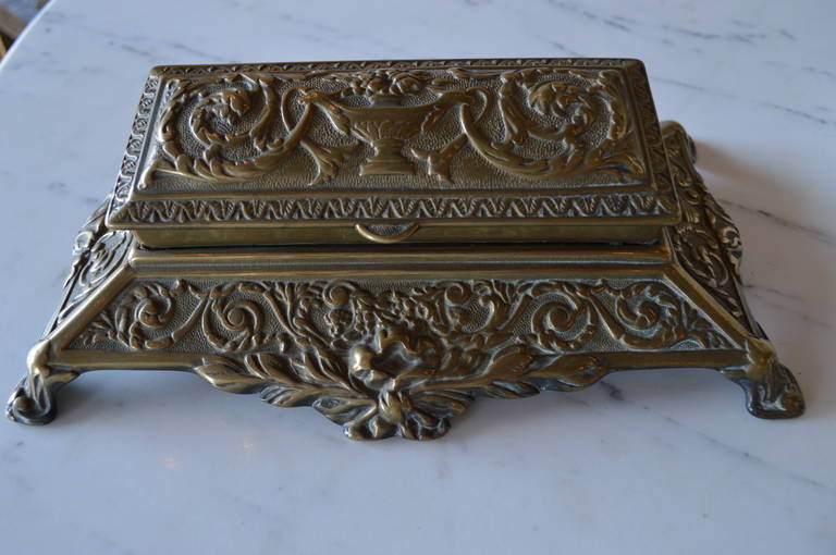 French bronze stamp box, the entire surface is ornate with bows, baskets of flowers and scrolls design Iit has five compartments, three smaller ones and two larger ones for storing stamps.