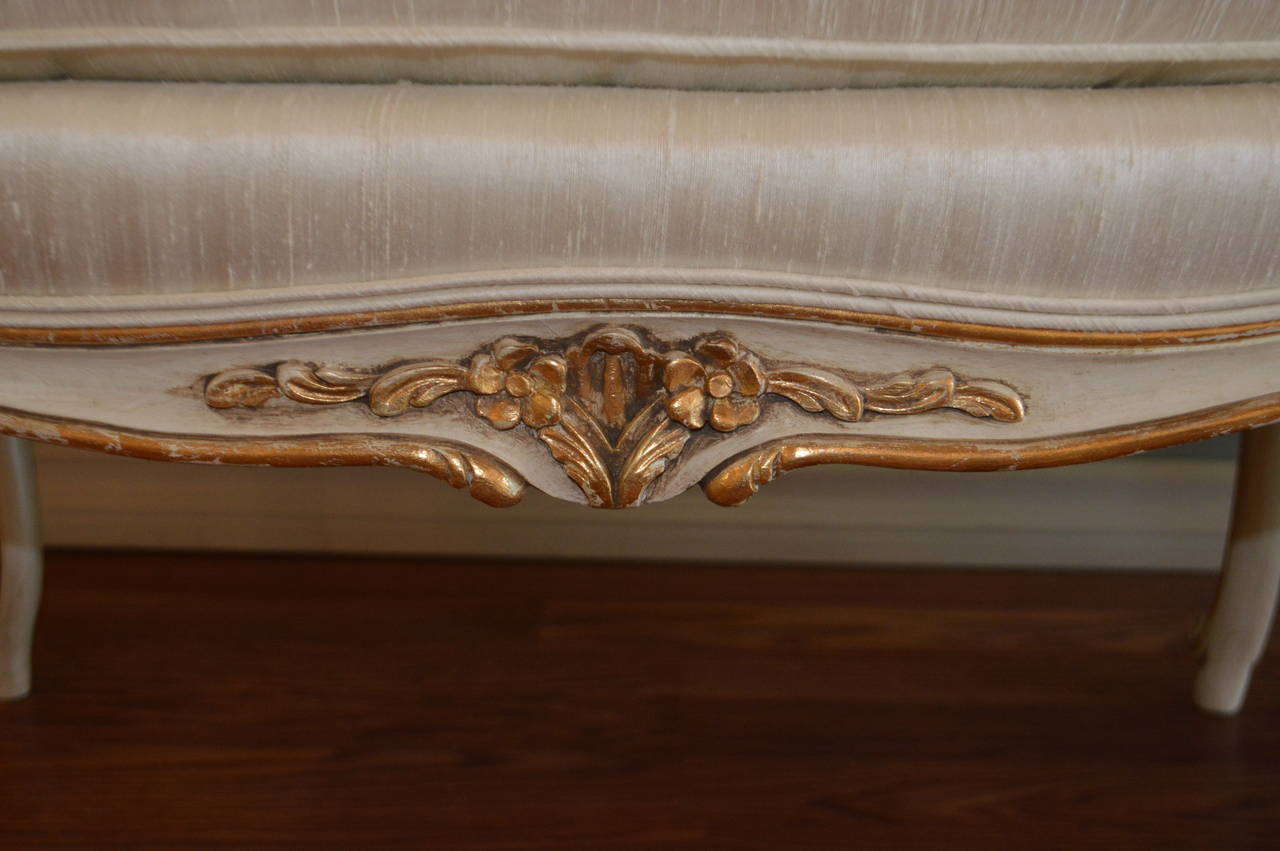 Louis XV style bench custom paint in a cream tone with antique finish gilding on all of the hand carved details on the apron and fine molding of the legs. Newly upholstered in a cream silk with dawn and feather seat cushion.
This bench 60