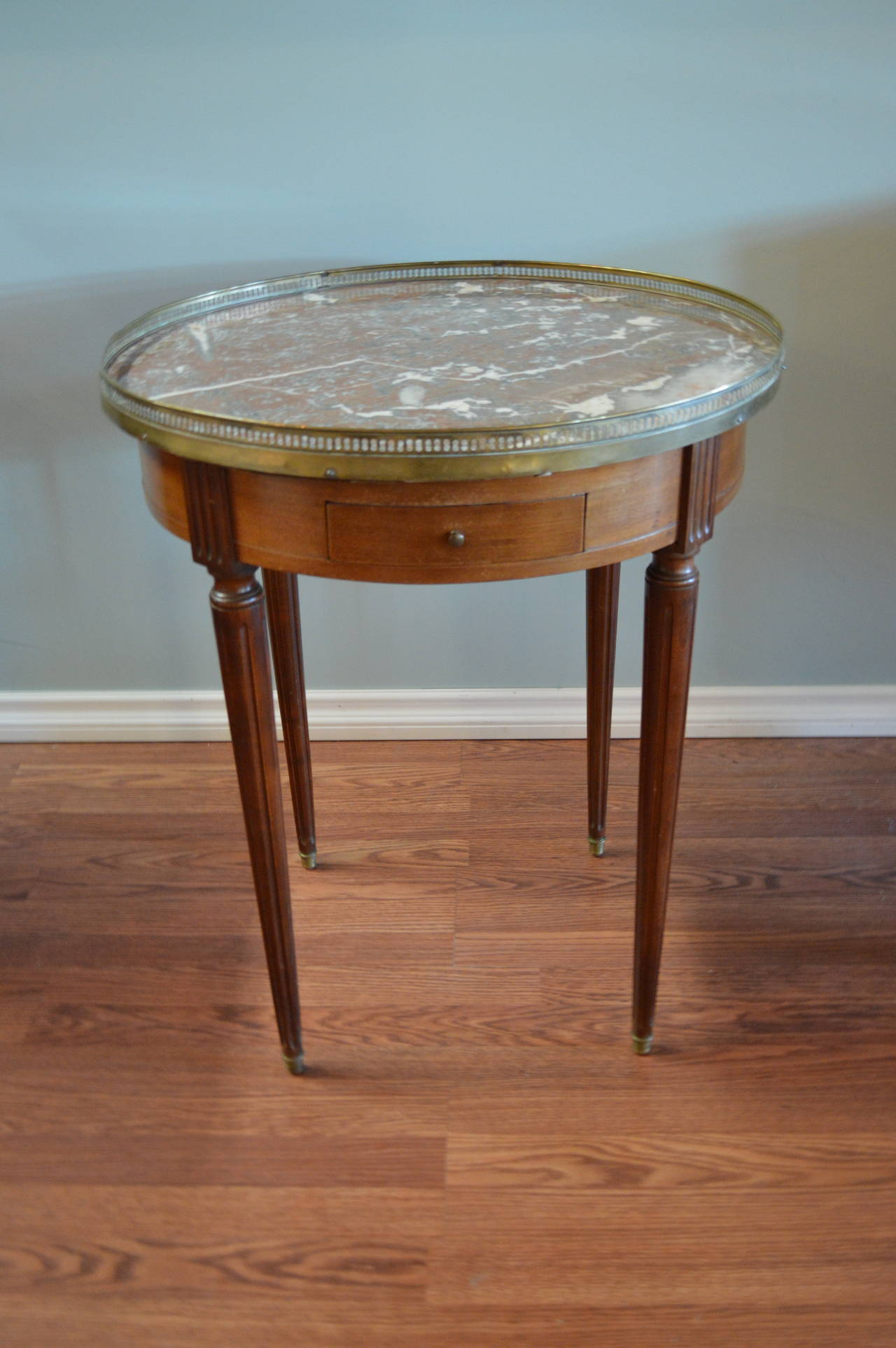 Louis XVI style mahogany bouillotte table with a very nice original marble top.
There is a bronze gallery and there are two small drawers and two small pull side tables with leather top. Four elegant fluted Louis XVI style legs.