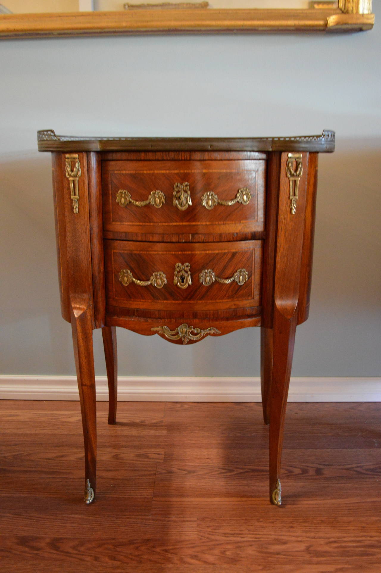 Louis XV style inlay kidney shape petite commode or side table with the original marble top. It has two drawers and lovely bronze hardware and a bronze gallery.