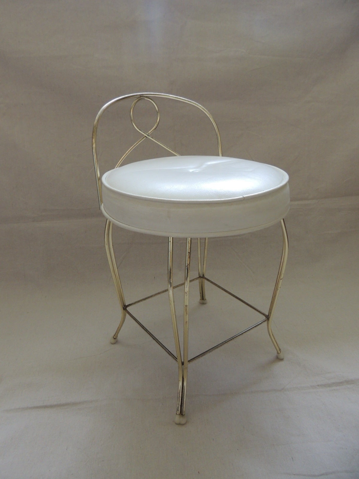 This item is part of our 7Th Anniversary SALE:
Vintage Art Deco style vanity stool with round cushion. 
Original faux leather seat cushion with tufted button in white. 
Brass frame.
Size: 14D x 17SH x 23BH