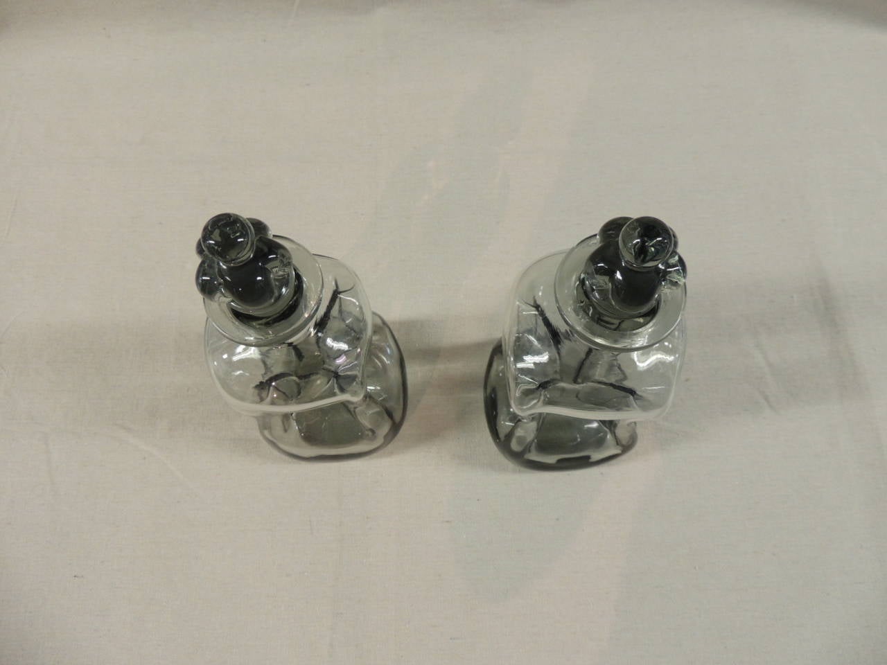 Pair of vintage pinched glass Holmegaard Kluk Kluk decanters, smoked glass with Royal Crown stoppers.