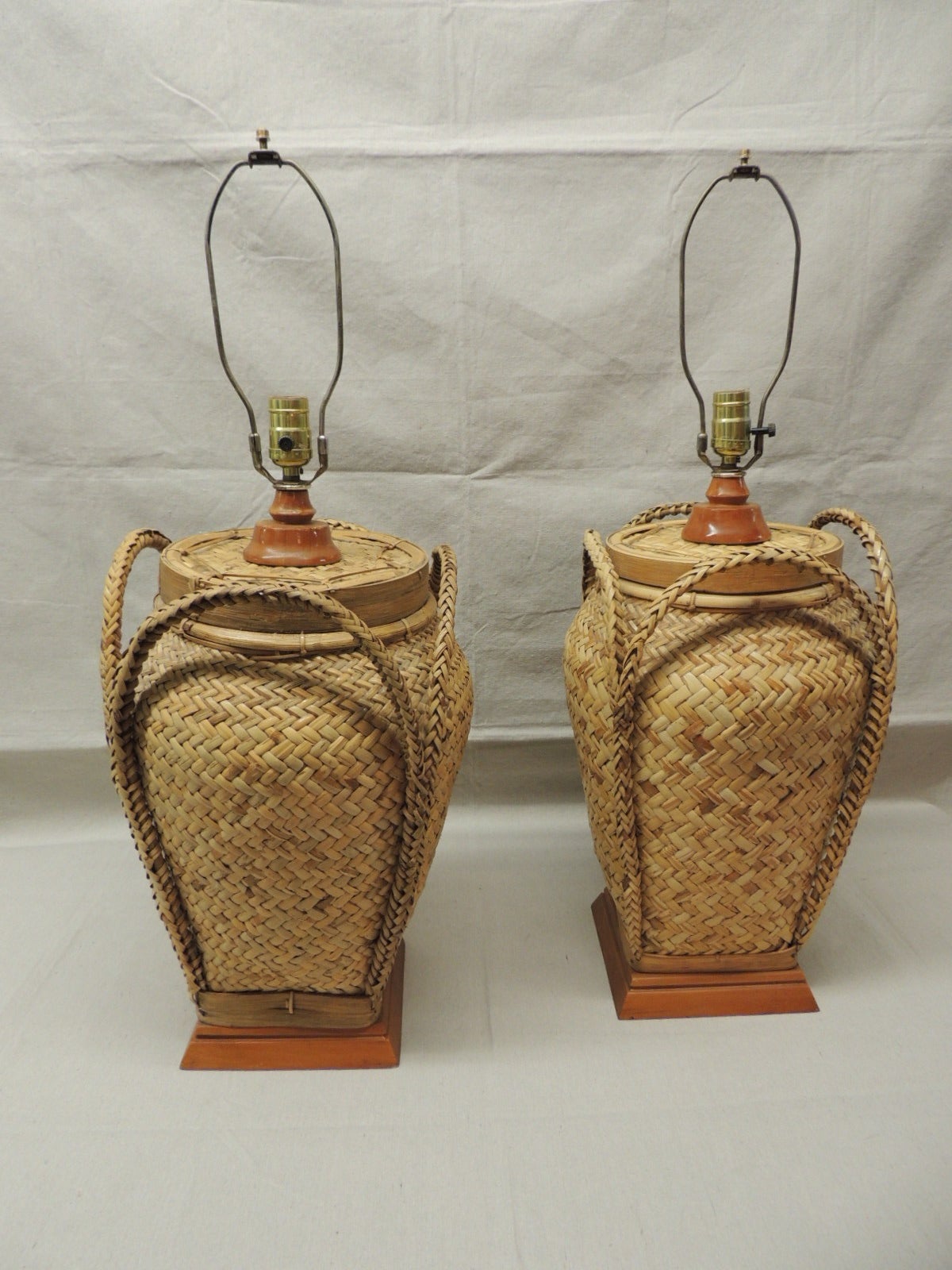 Pair of tall rattan reed detail lamps mounted on wood bases with handles. Basket weave design. (Shades not included). 3 way switch. 30