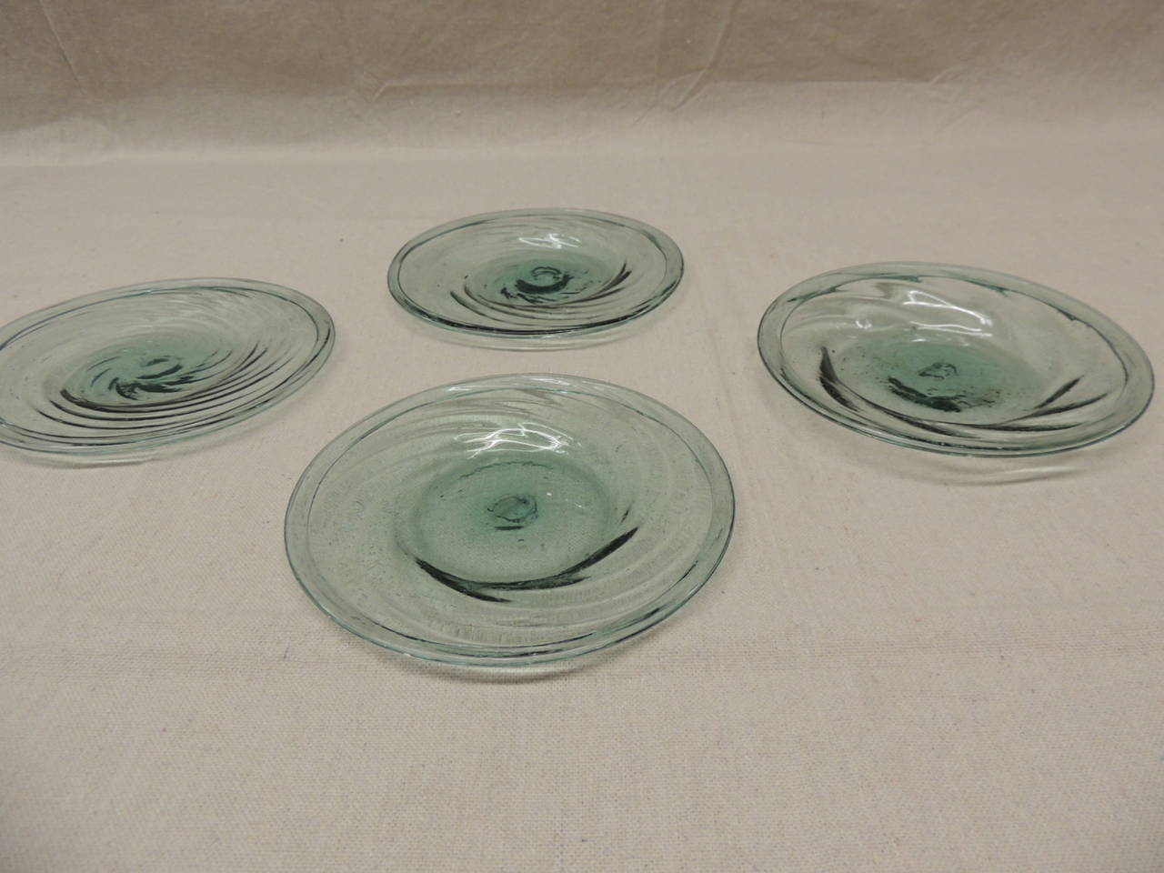 Set of (4) round swirl design, hand-blown dessert dishes. They look like sea glass in color.