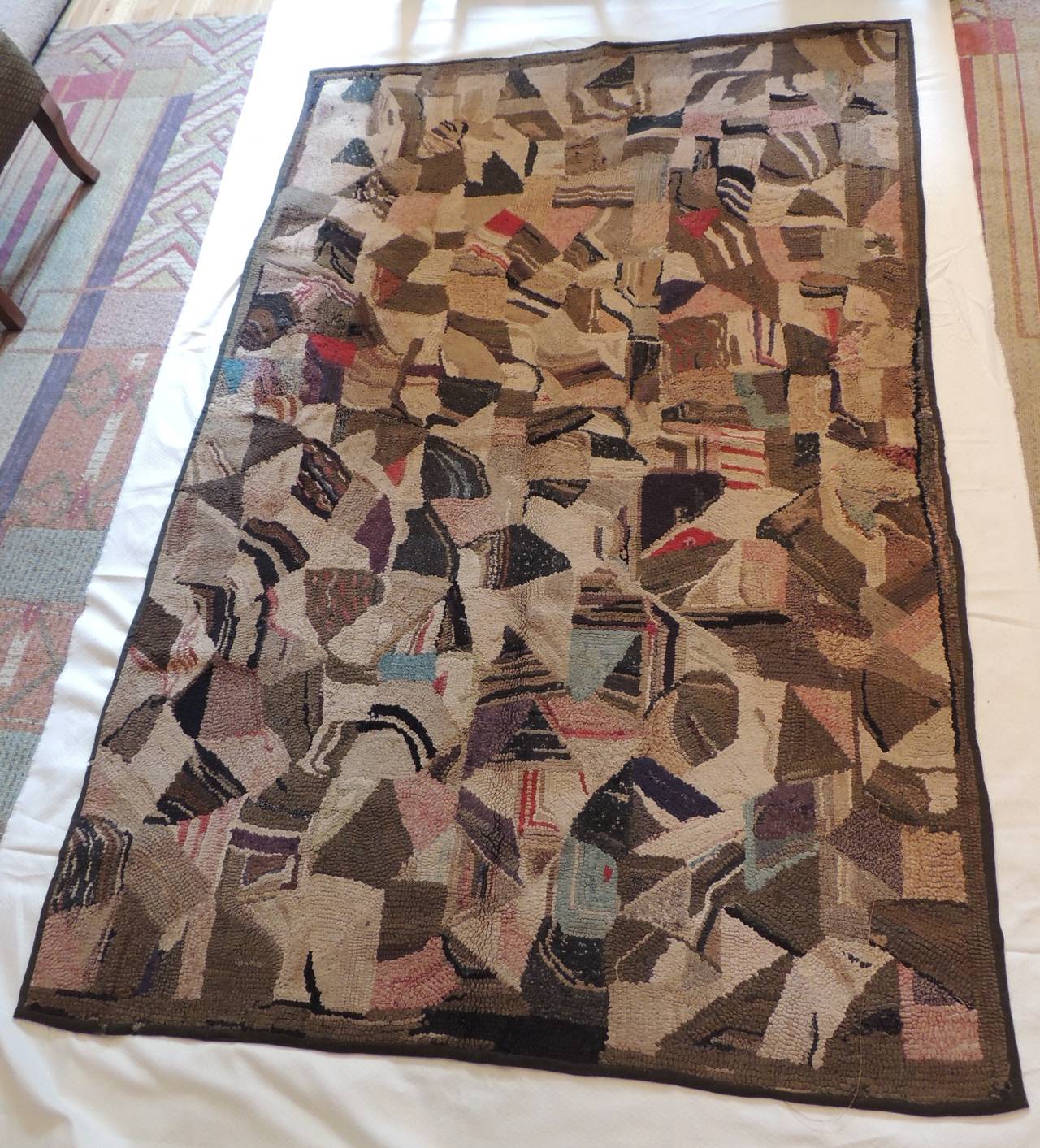 Crazy quilt pattern American hook rug in shades of brown and pink. Thick pile.
Rug hooking is both an art and a craft where rugs are made by pulling loops of yarn or fabric through a stiff woven base such as burlap, linen, or rug warp. The loops are