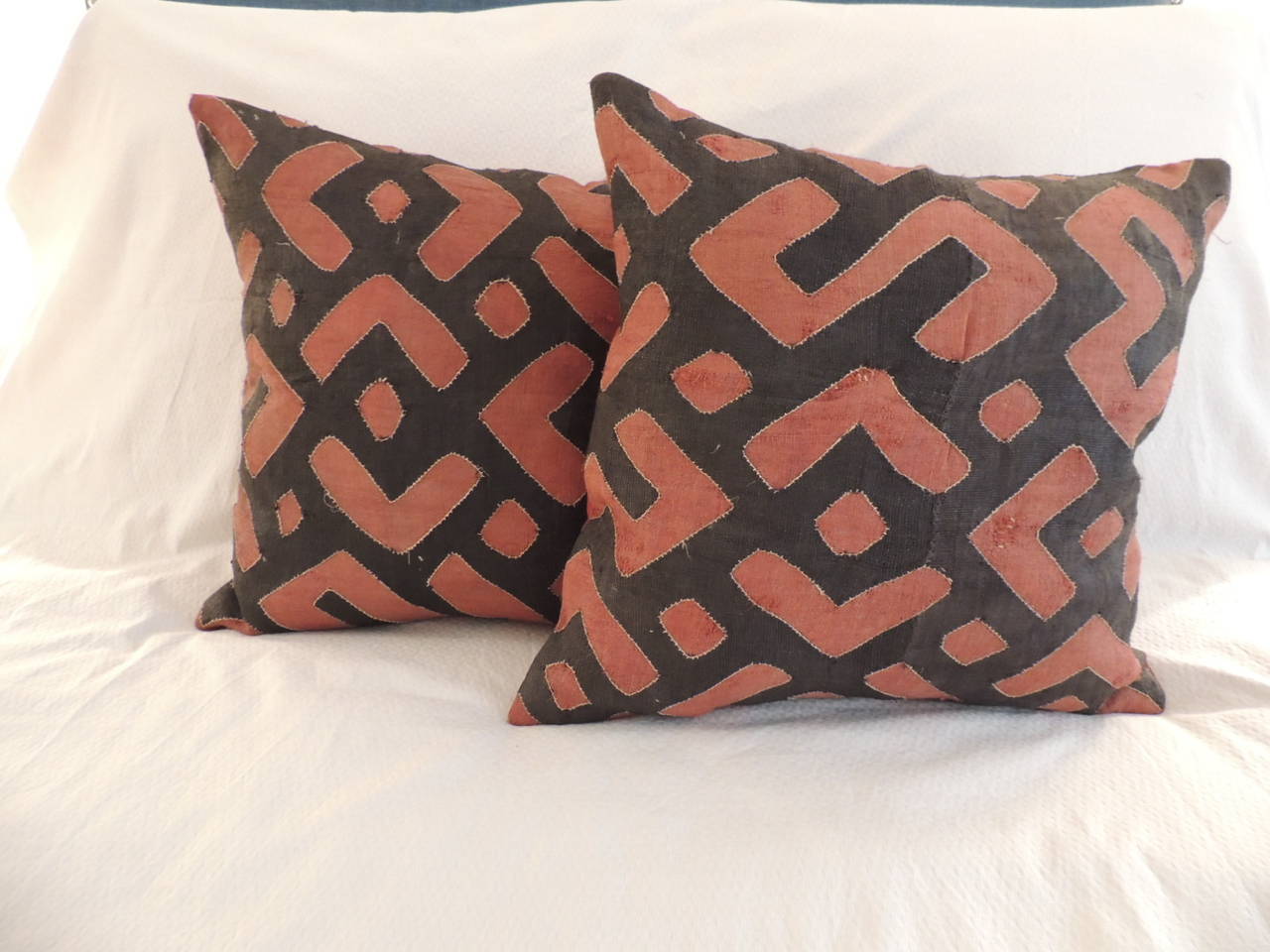 Pair of indigo and rust African raffia applique linen pillows with deep orange texture linen backings.