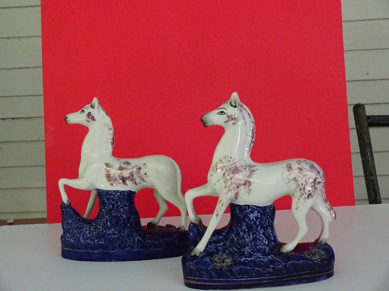 Pair of lusterware Staffordshire prancing horses.  Pink and gold splatter on white
porcelain ground.  The horses on cobalt blue bases.