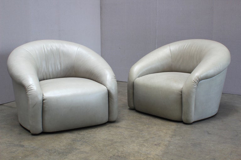 A Pair of Barrel Back Swivel Club Chairs. USA, 1970s. An oversized pair of Milo Baughman style club chairs on swivel bases. Leather is in used condition and has some spotting and staining consistent with age.