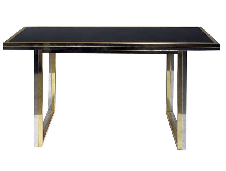 Pair of Brass and Chrome Console Tables. USA, 1970's. An elegant pair of console tables with inset smoked glass tops. Each console has legs and apron composed of matched chrome and brass strips. The shape is simple and well composed and the depth at