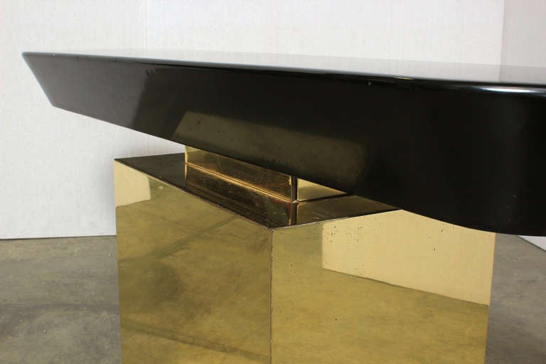 A Cantilevered Console in Brass and Lacquer. c. 1970s. A black lacquered wood top cantilevers over a bras clad wooden base.