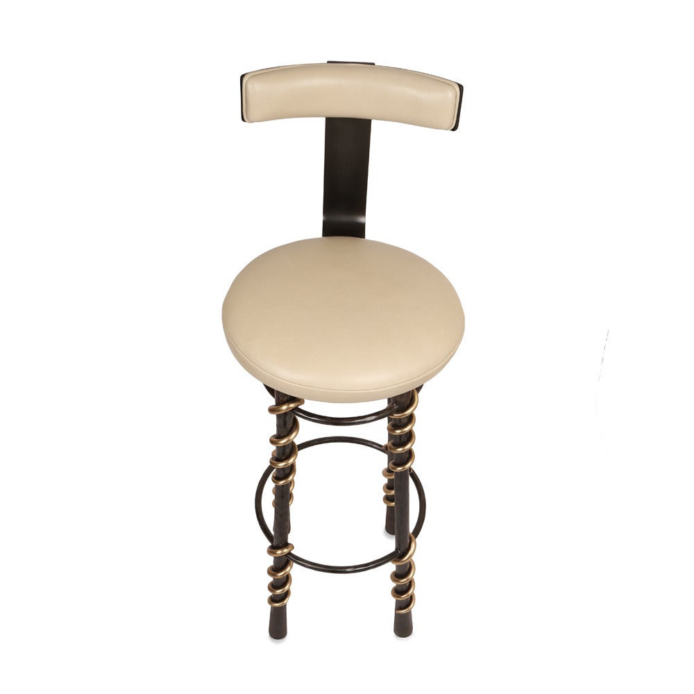 This sexy yet easy stool has legs made of hand-wrought blackened steel with bronze serpent-inspired detailing. Each solid, chip-carved leg is finished with a hand-applied, deep oil-rubbed bronze patina. The seat is upholstered in supple black