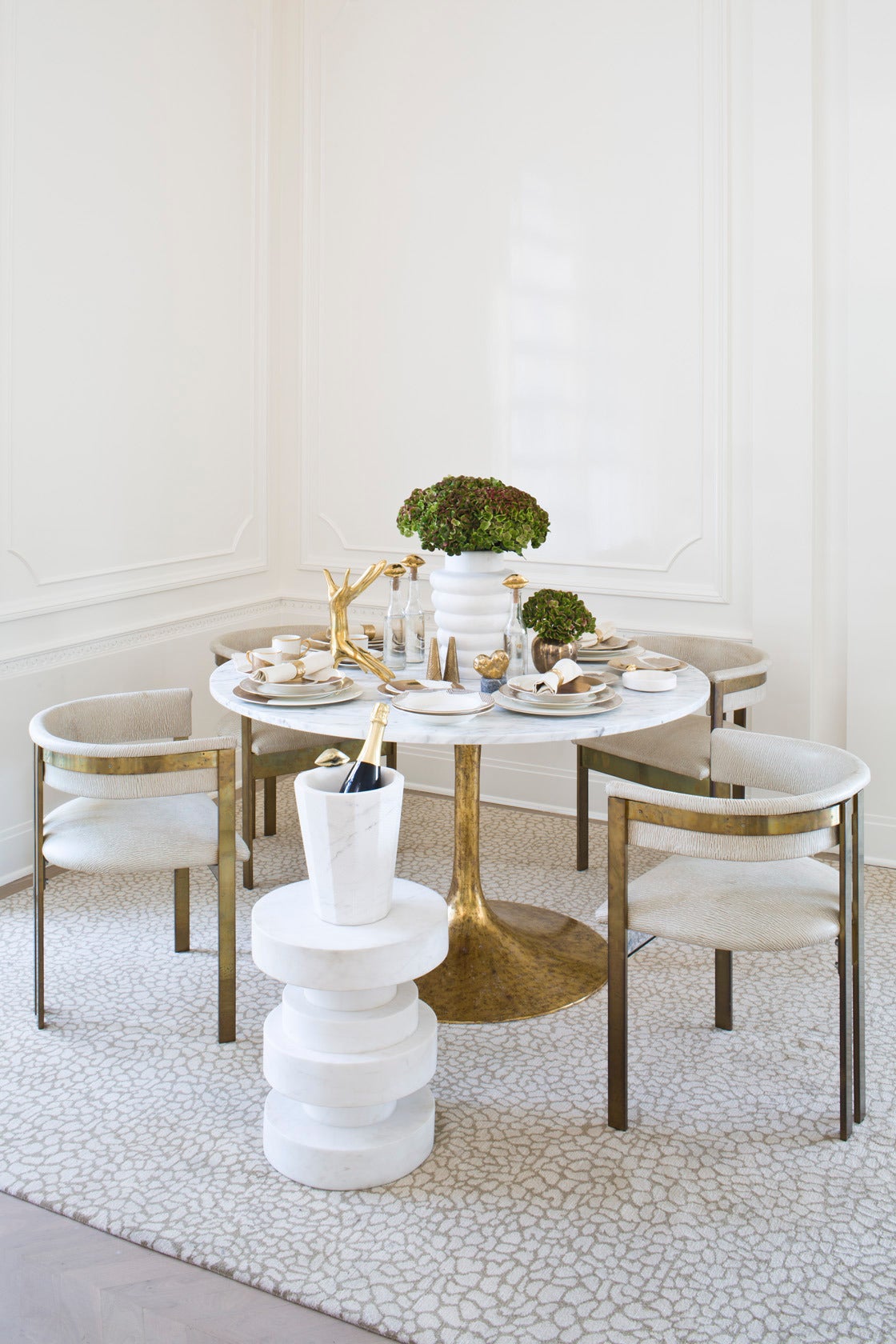 This simple tulip-style occasional table matches a solid white Carrera marble top with a gold leafed metal base. The leafed base features an antiqued finish and a dramatic taper. At 50