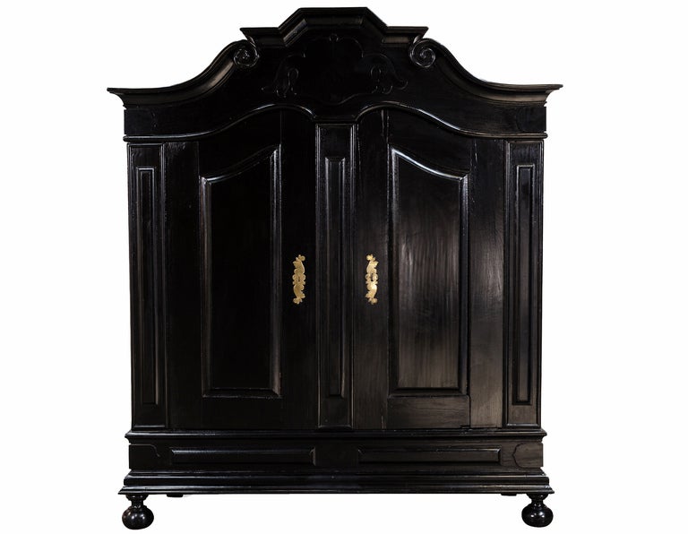 Early 19th Century Ebonized Oak Armoire. Spain, 19th Century. This gorgeous and oversized armoire is documented in Kelly Wearstler's second book Domicilium Decoratus. Heavily carved scroll work on the pediment and ball feet. Has the original brass