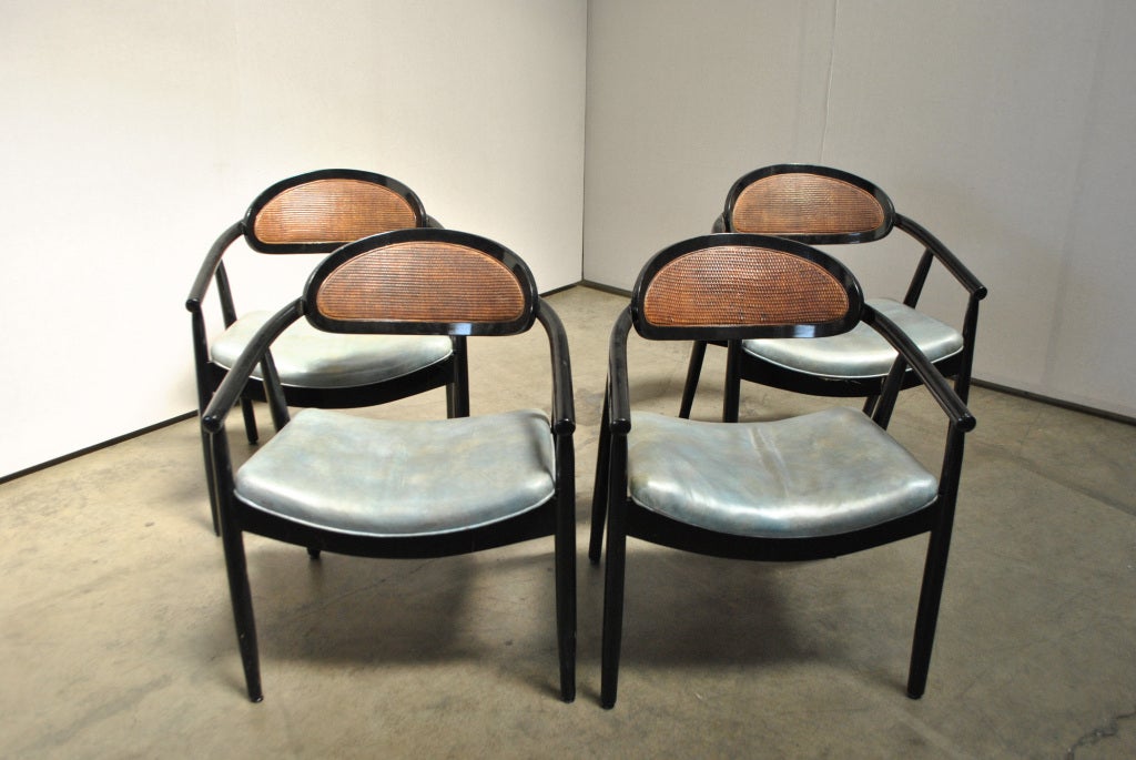 A Set of Four Gaming Chairs in the style of James Mont. USA 1950s. A handsome set of gaming chairs with curved backs and woven wicker backrests. Each chair is upholstered in the original aquamarine leather and ebonized in black lacquer. Nearly