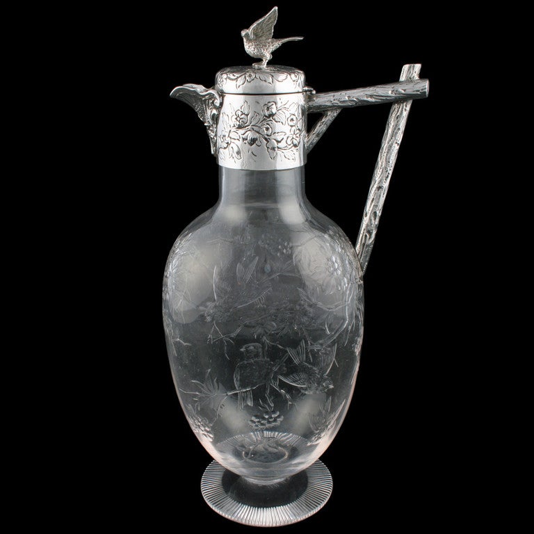A fine late 19th century Victorian sterling silver mounted cut glass claret jug.

The jug has an oval shaped glass body with a circular foot that has a ground and star cut base. The jug is finely decorated with engraved birds flying between flowers