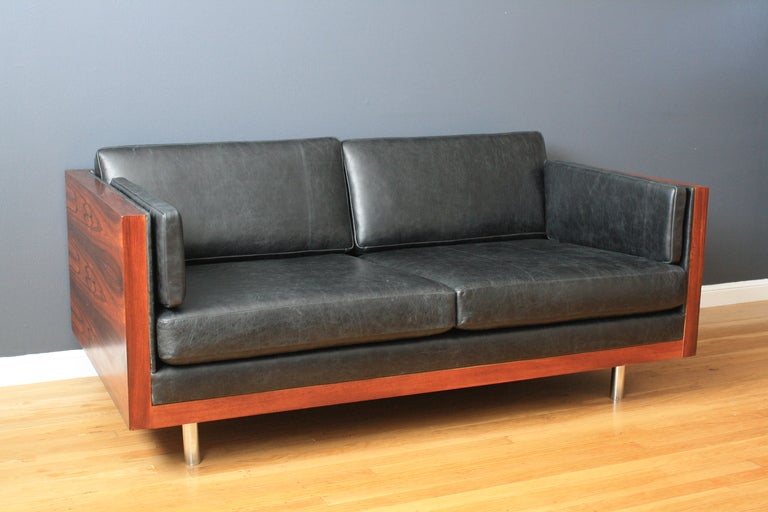 This vintage Mid-Century settee/sofa was designed by Milo Baughman for Thayer-Coggin. It has a rosewood case frame, black leather upholstery and chrome legs. This vintage love seat has been professionally reupholstered and is in great condition.