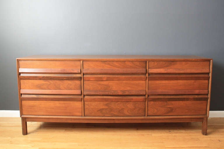 This is a vintage Mid-Century nine drawer dresser by American of Martinsville. It is walnut with rosewood pulls.